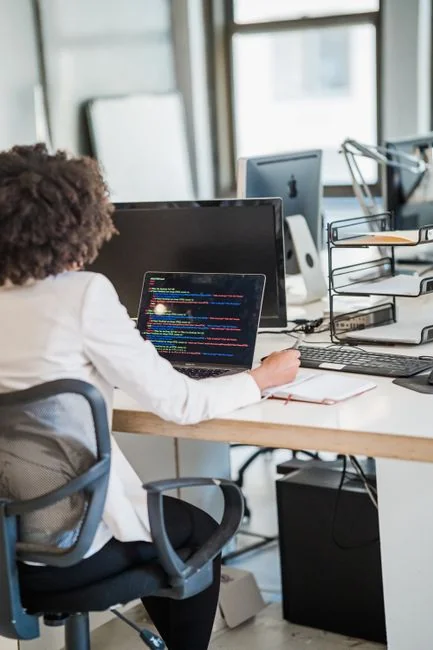 Un espace de travail contemporain avec deux écrans d’ordinateur affichant des projets de web design, mettant en avant la technologie et la productivité.